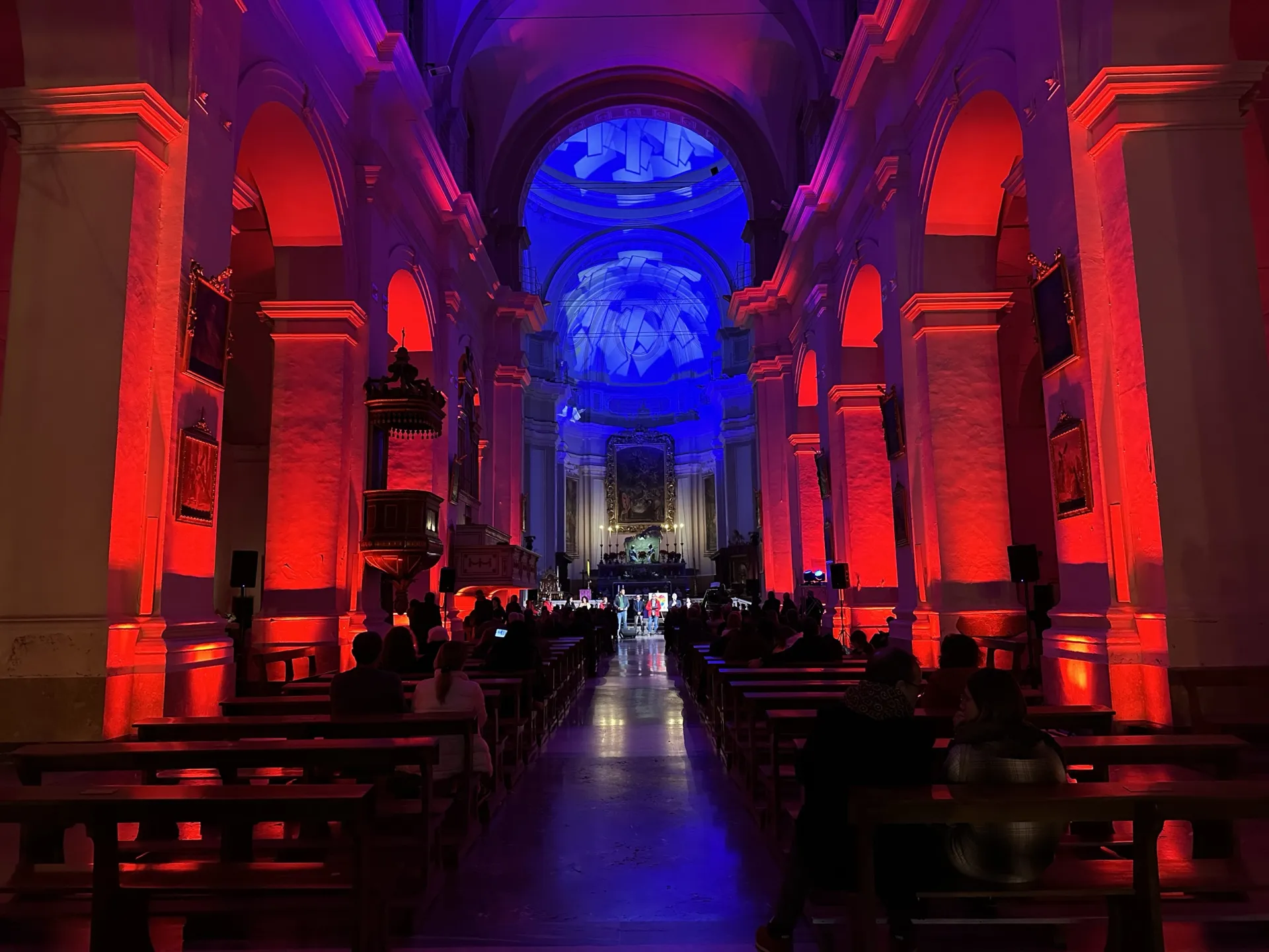 Navata di una chiesa illuminata di rosso con proiezioni blu sulla cupola